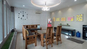 A modern living room with a sofa, chairs, a coffee table, a chandelier, a wall clock, and artwork. - RedDoorz @ Nagoya Indah (Batam)