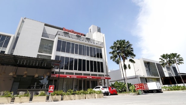Un edificio moderno con una amplia fachada de vidrio, un toldo rojo con el texto 