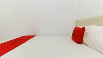 A neatly made bed with a white mattress and a red bed runner.