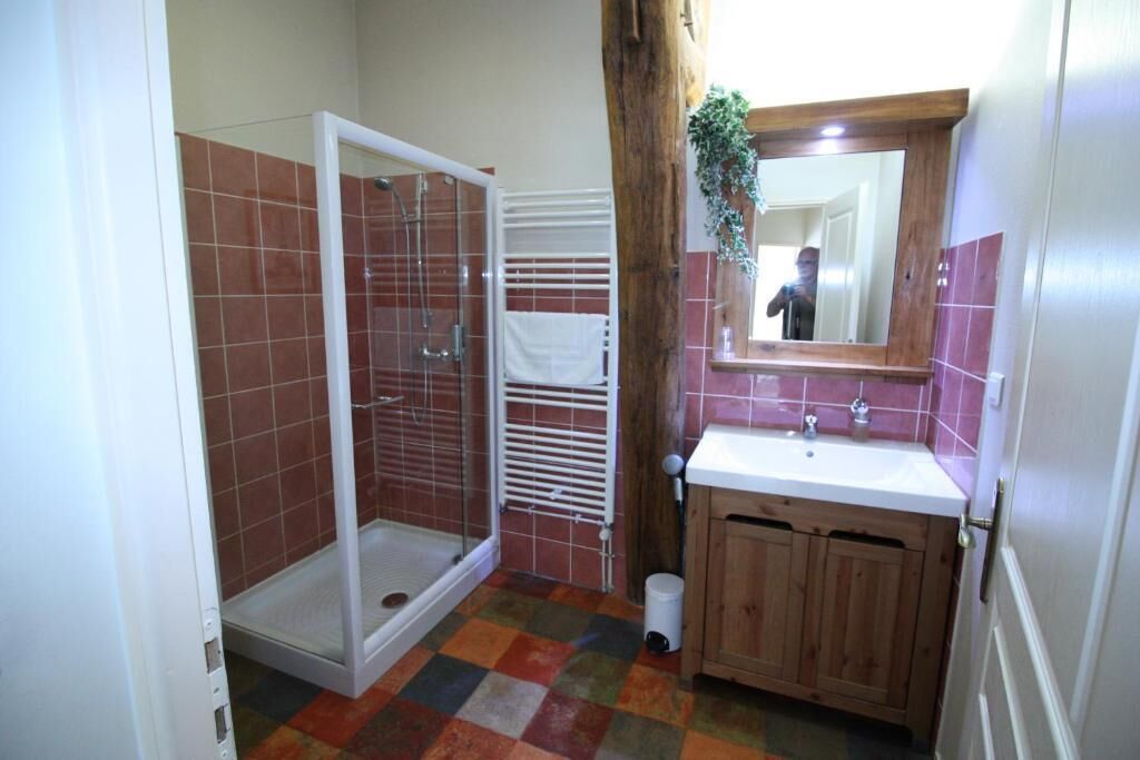 Un baño con ducha, lavamanos y armarios de madera.