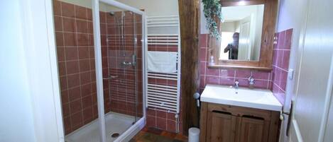 Un baño con ducha, lavamanos y armarios de madera.