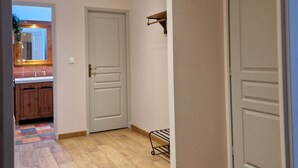 A hallway with wooden flooring, a ceiling vent, and two closed doors. - Ferme D'Orsonville (Villiers-en-Bière)