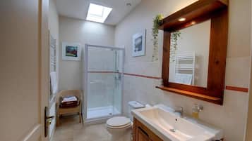 A bathroom with a shower, toilet, sink, and a mirror.