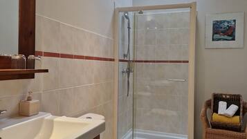 Een badkamer met douche, toilet en wastafel.