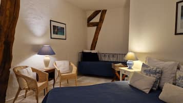 A bedroom with a large bed, a chair, a small table, and a lamp.