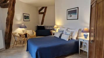 Un dormitorio con una cama grande, dos mesitas de noche con lámparas, una silla y estructura de vigas de madera.