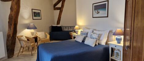 Una camera da letto con un letto grande, due comodini con lampade, una sedia e travi in legno a vista.