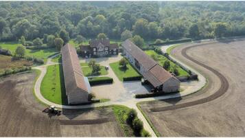 An aerial view of a large estate with multiple buildings, a winding driveway, and surrounding fields.