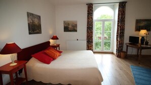 A bedroom with a bed, two bedside lamps, a desk with a lamp, a window with curtains, and two paintings on the walls. - Ferme D'Orsonville (Villiers-en-Bière)