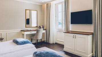 A hotel room with a bed, a desk, a chair, a television, and a window with curtains.