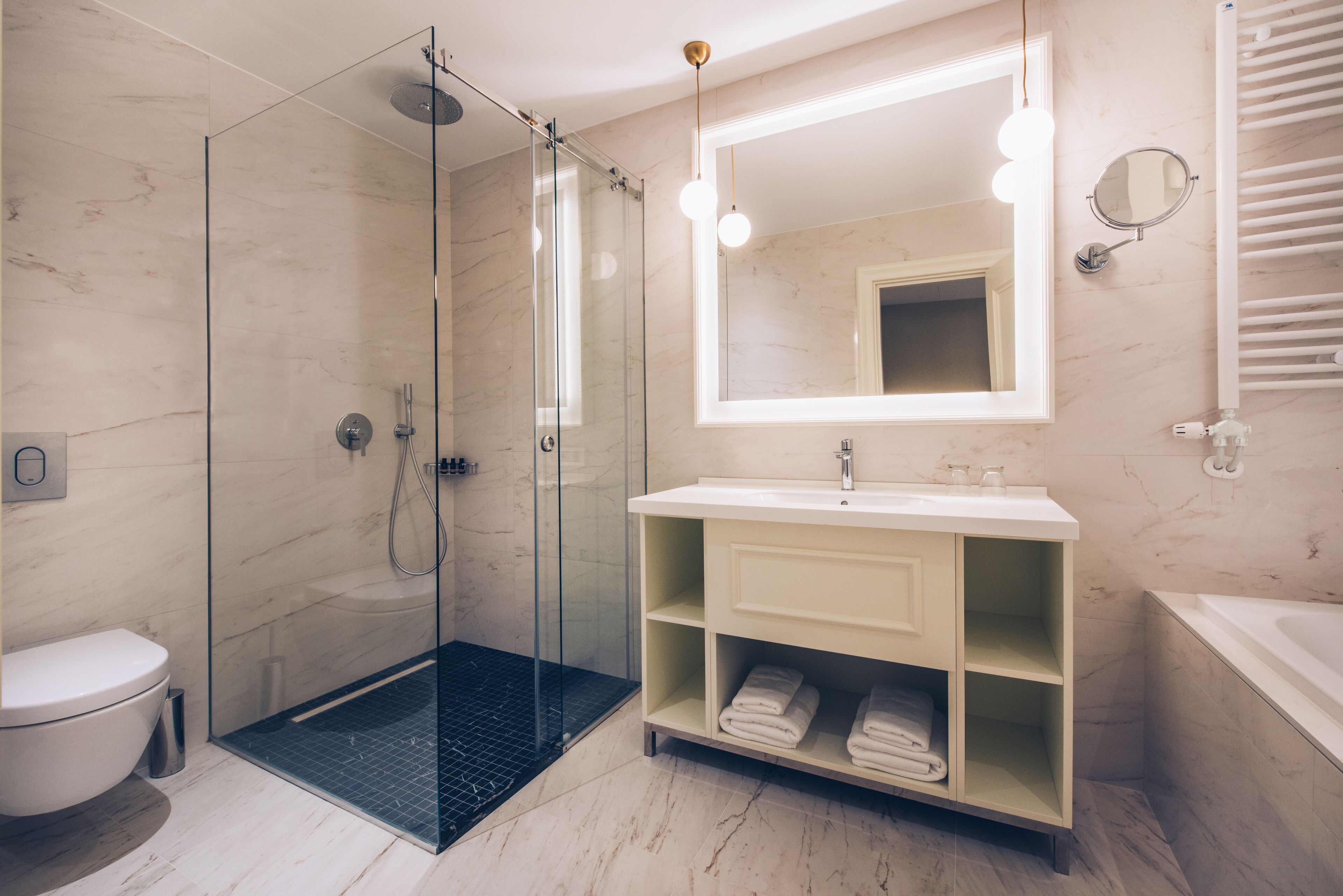 A modern bathroom with a glass-enclosed shower, a white sink with a mirror above, and a bathtub.