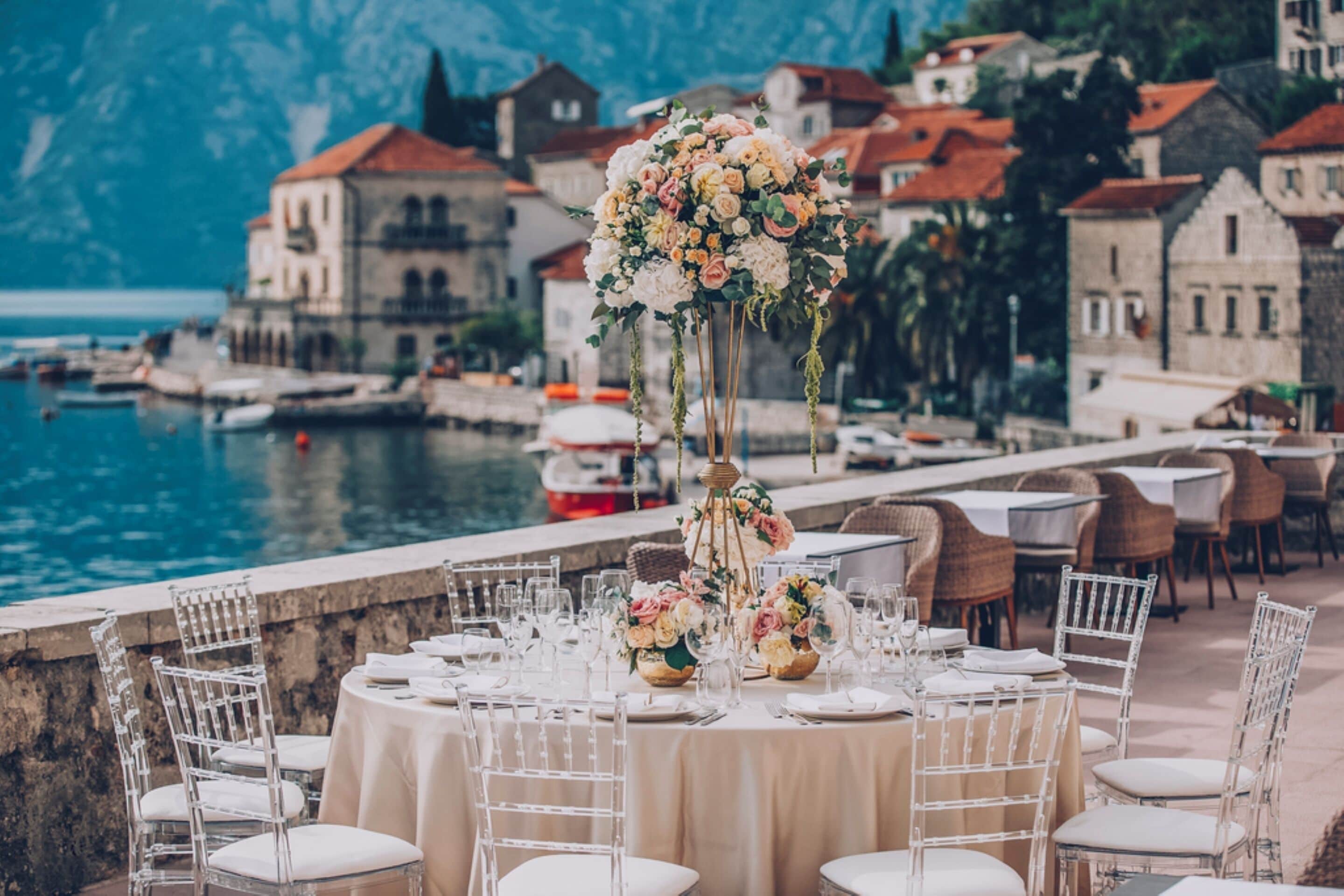 A table set for a wedding with a backdrop of a coastal town and a body of water.
