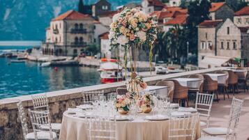 Ein Hochzeitstisch vor der Kulisse einer Küstenstadt und eines Gewässers.