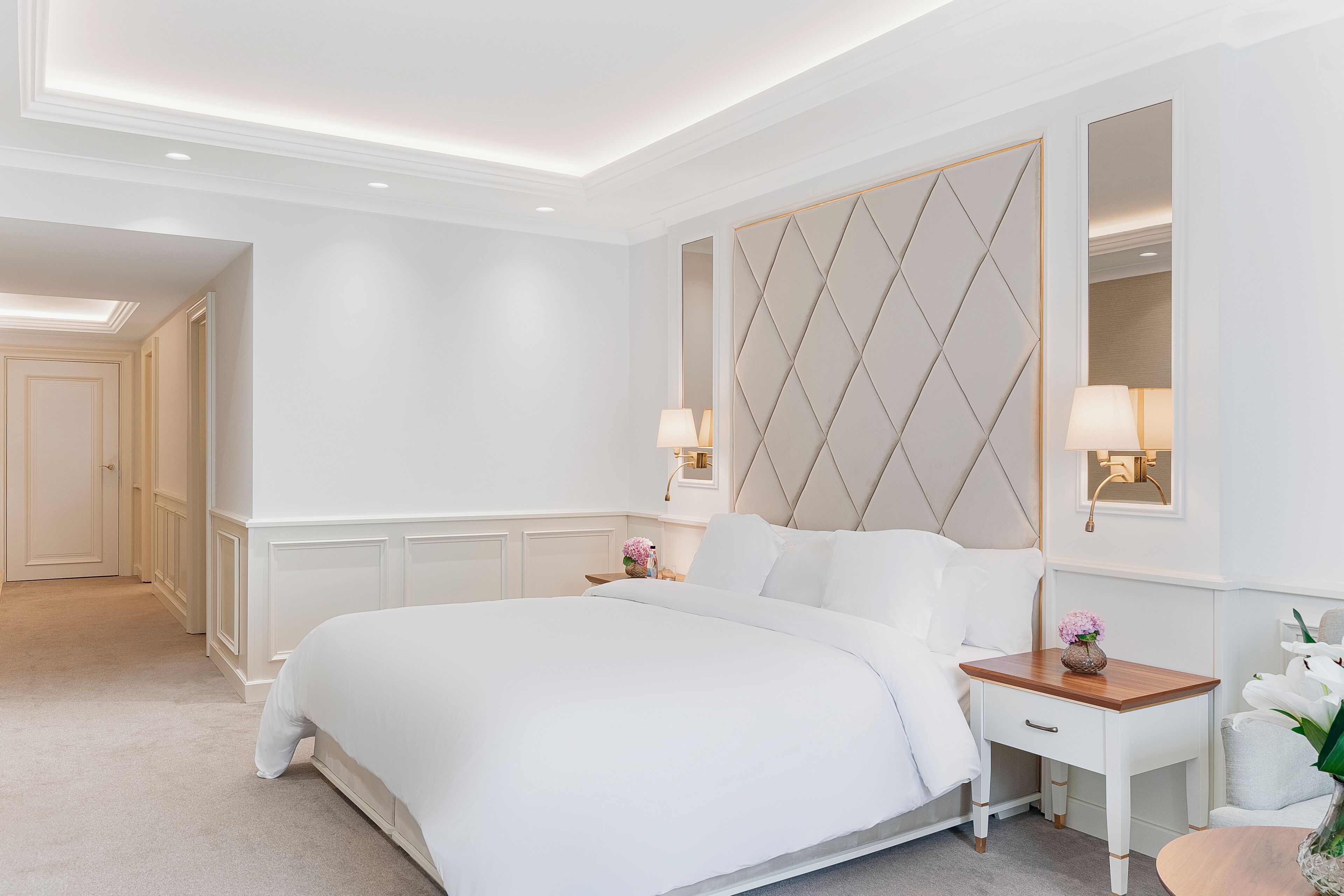 A modern hotel room with a large bed, a wooden nightstand, and a decorative wall panel.