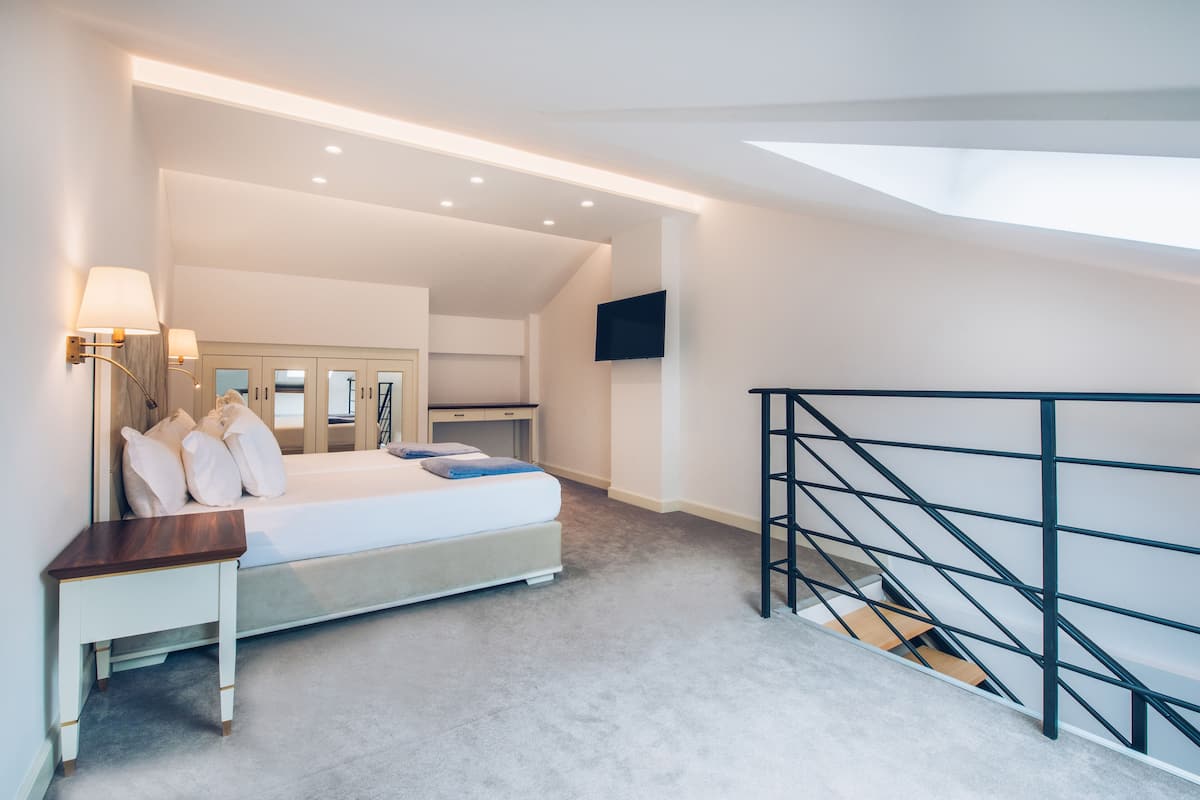 A bedroom with a bed, bedside table, lamp, and a TV mounted on the wall.