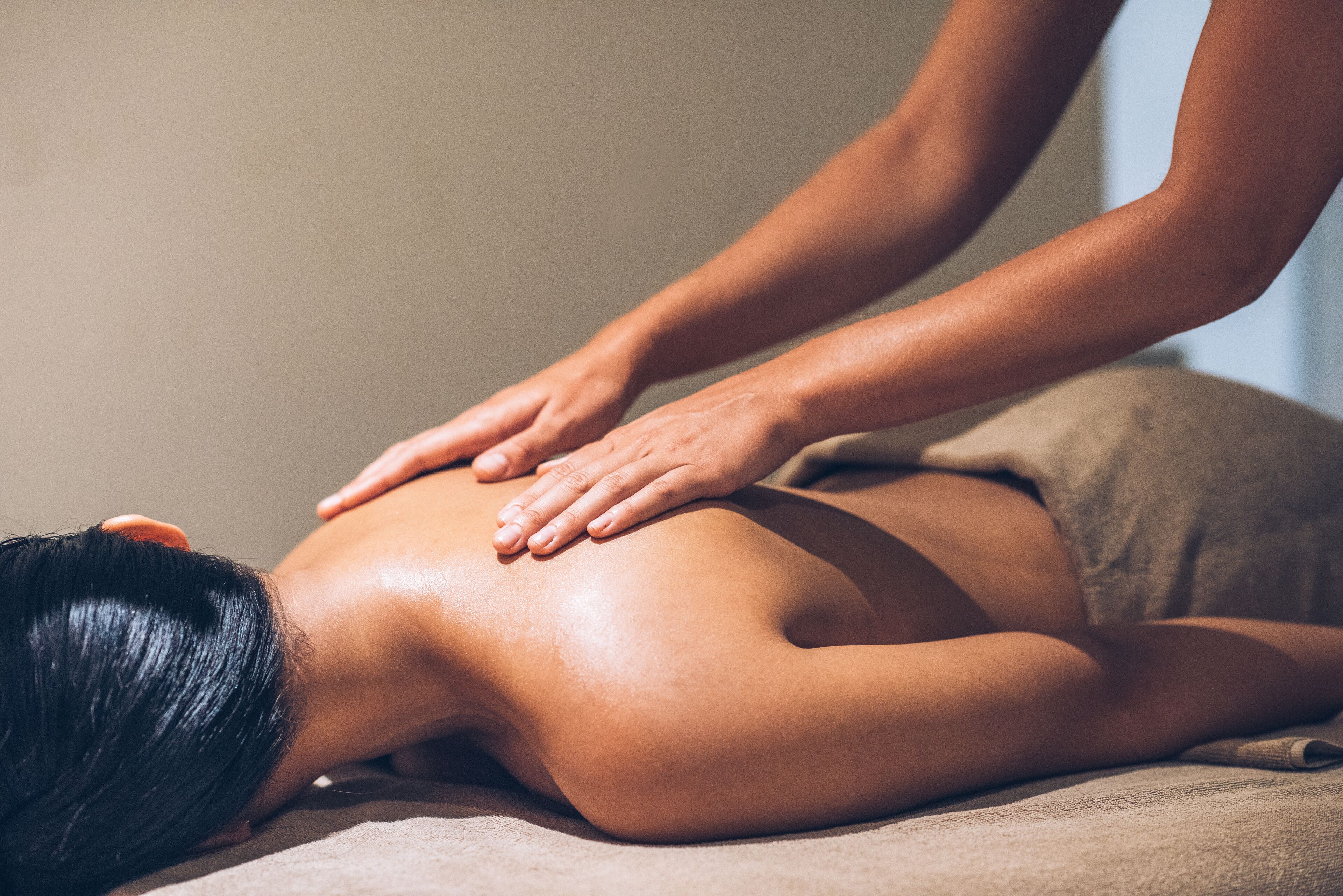A person receiving a back massage on a massage table.