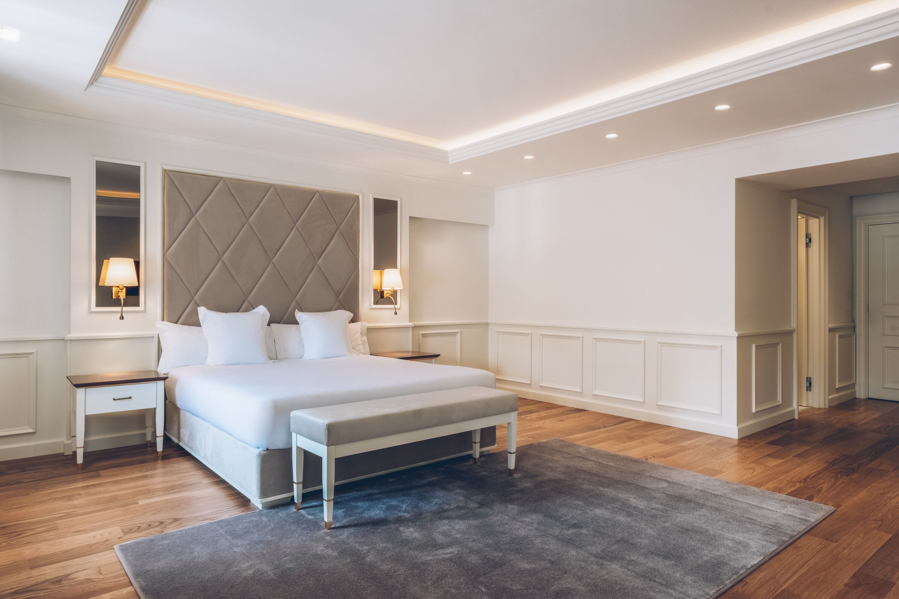 A modern bedroom with a large bed, bedside tables, and a bench.