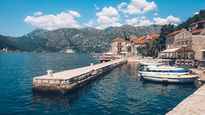 A coastal town with stone buildings, a pier, and boats docked. - Heritage Grand Perast (Perast)