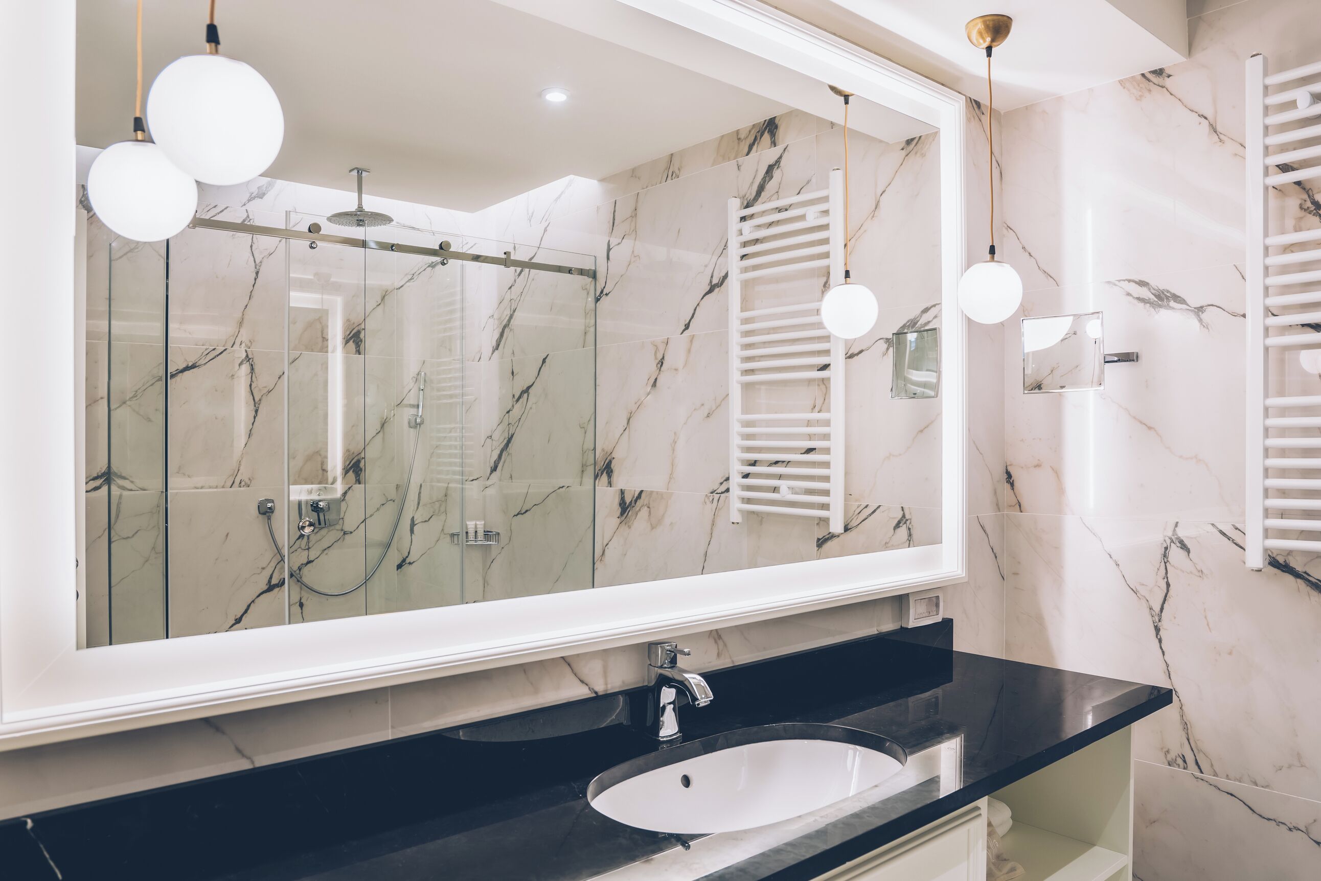 Un baño con un espejo grande, una encimera negra y un lavabo blanco.