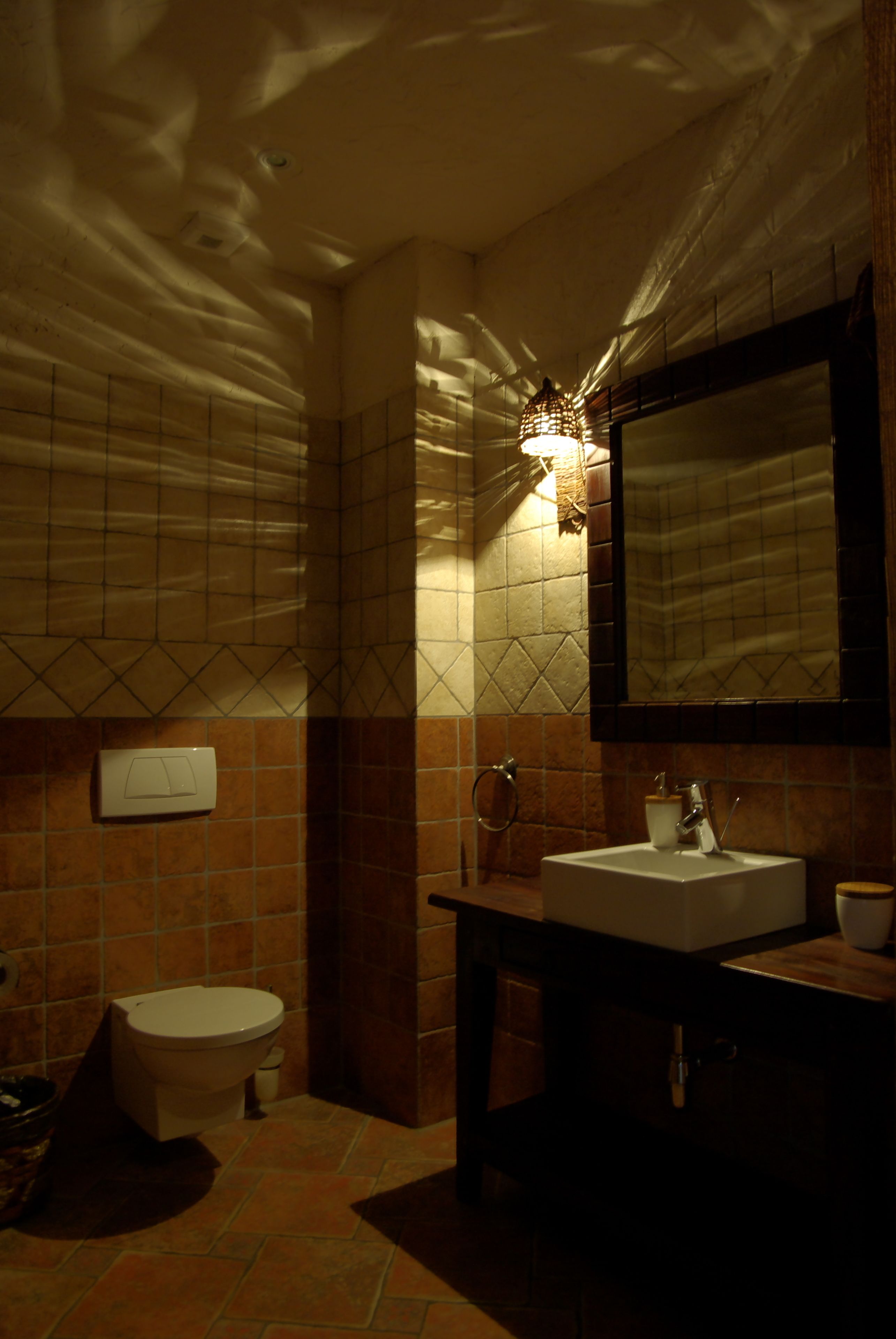 A bathroom with a toilet, sink, and mirror.