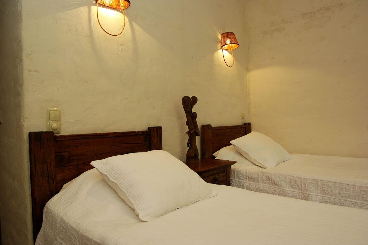 Two single beds with wooden headboards, white bedding, and wall-mounted lamps.