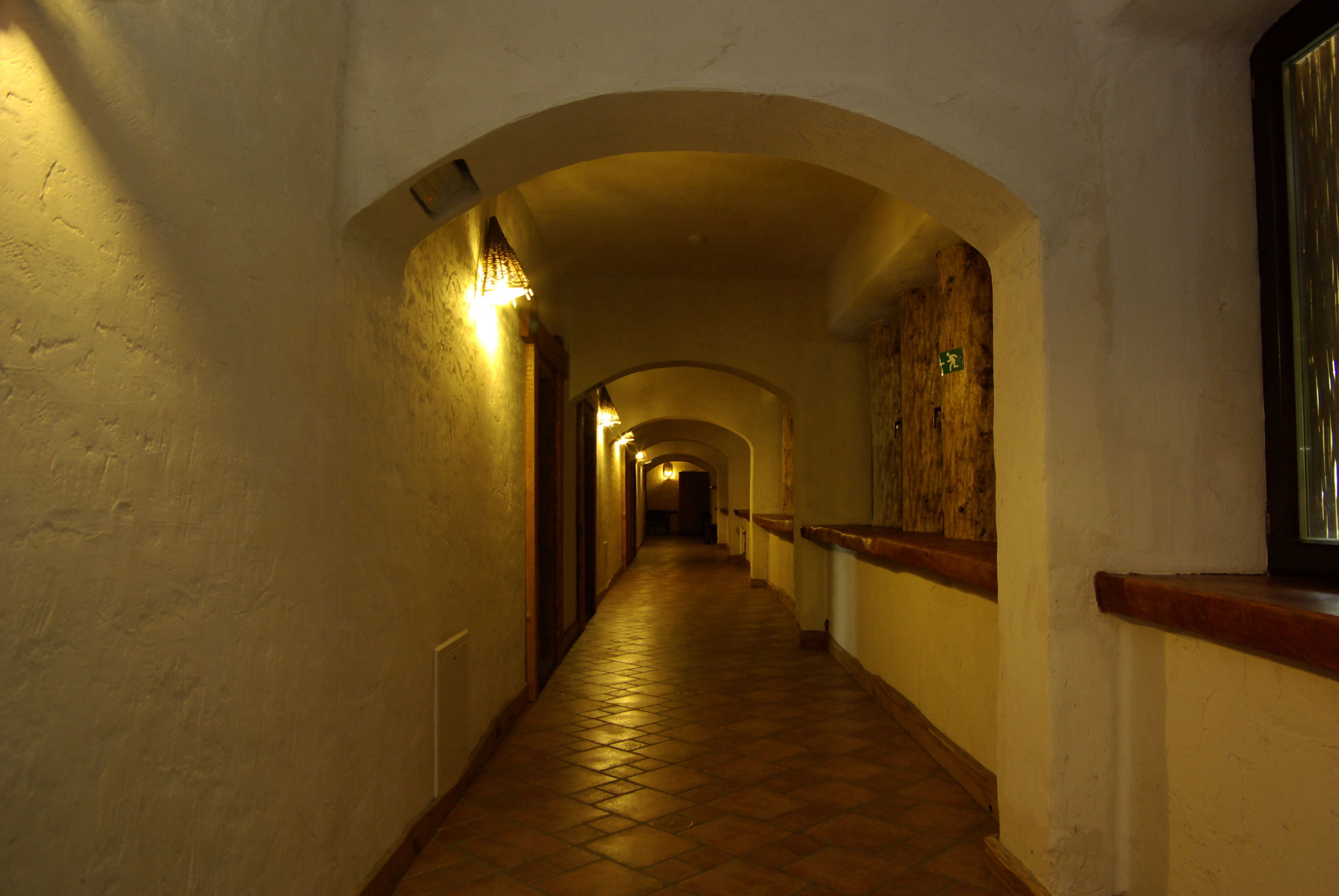 A long, narrow hallway with a tiled floor and a wooden bench on the right.