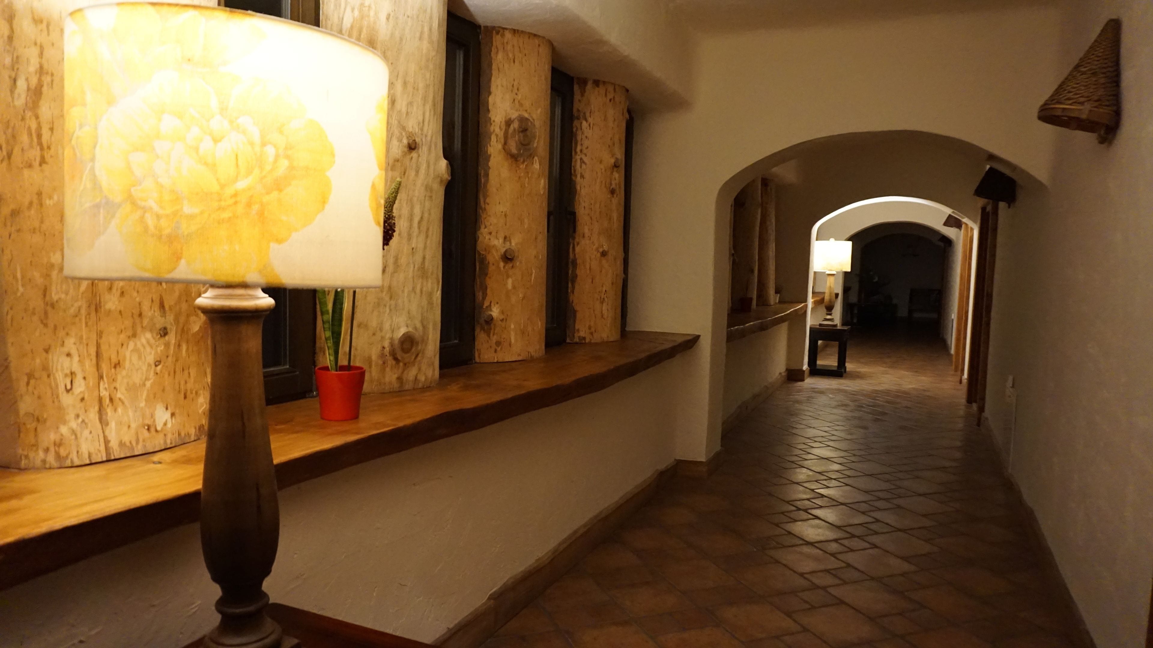 A hallway with a wooden bench, a lamp, and a potted plant.