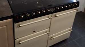 A kitchen with a black stove, beige cabinets, and white tiled backsplash.