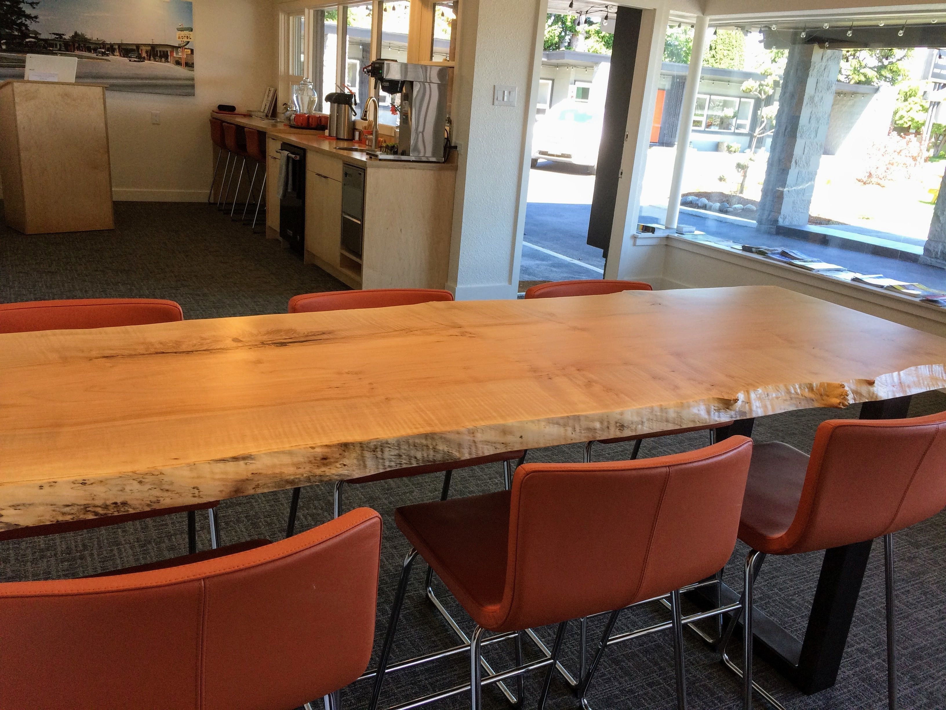 Un salón de conferencias con una gran mesa de madera y sillas color naranja.