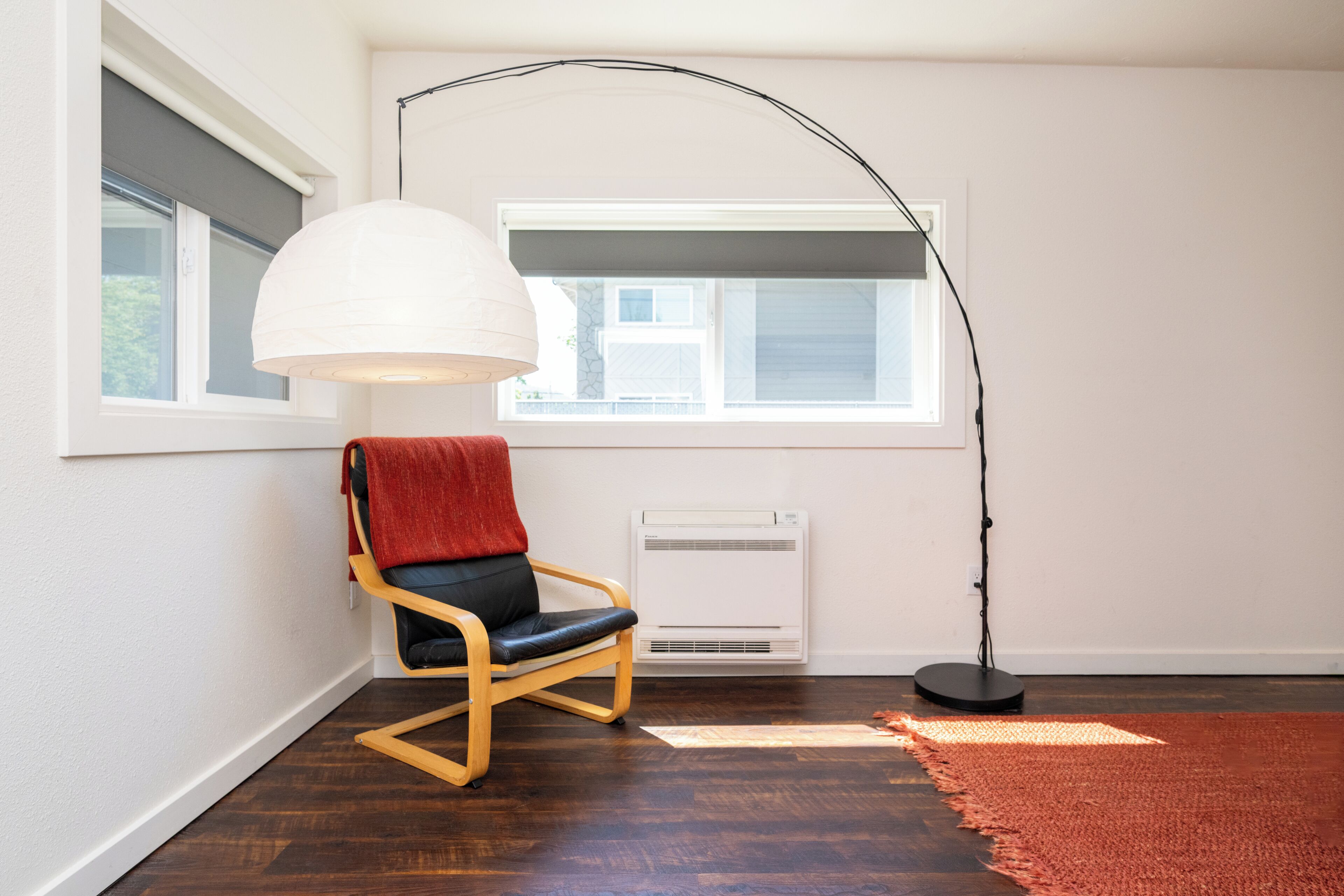 A room with a wooden chair, a white floor lamp, and a red rug.