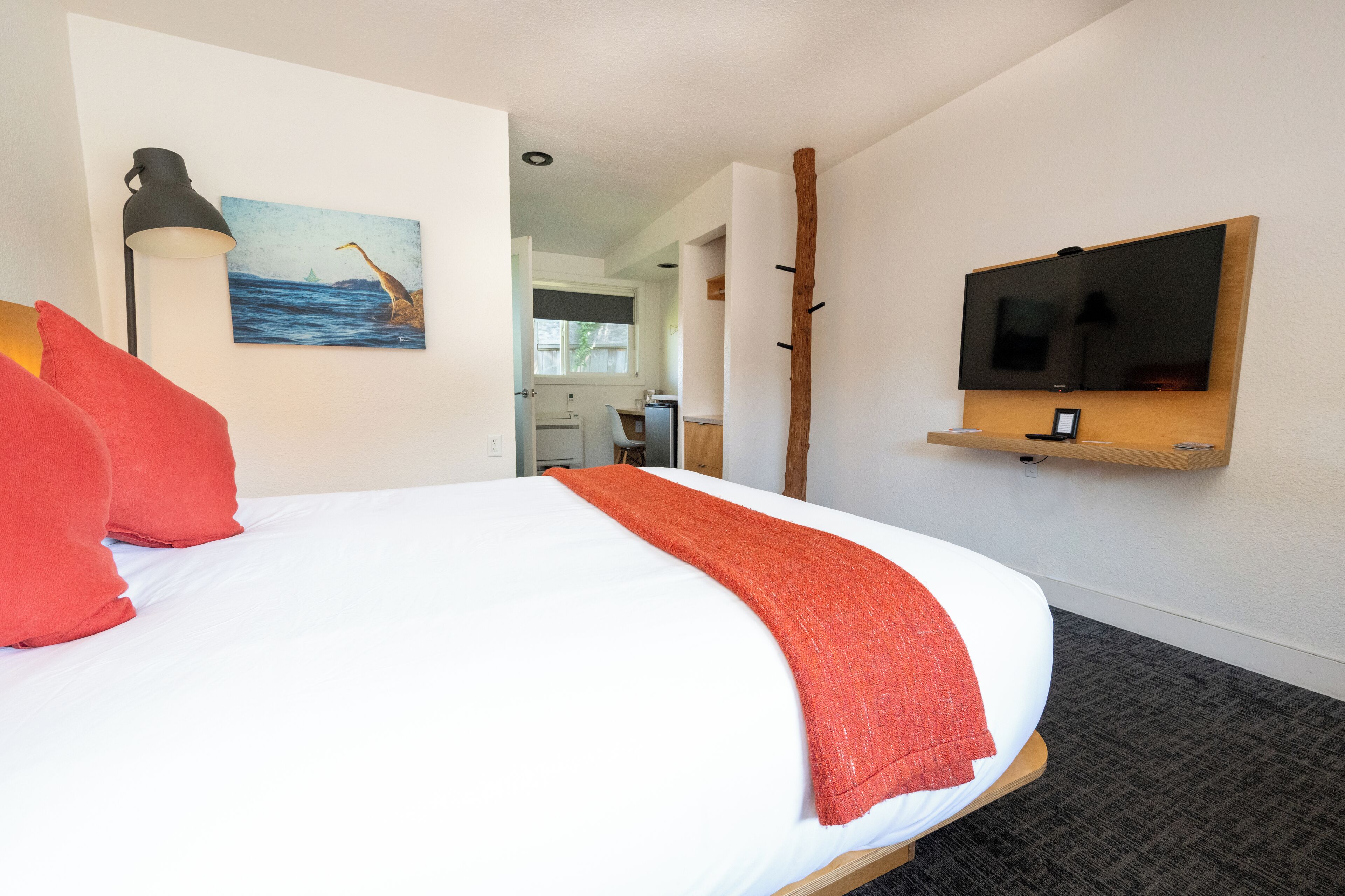 Ein Hotelzimmer mit einem großen Bett, einem an der Wand befestigten Fernseher und einem Bild eines Bootes an der Wand.