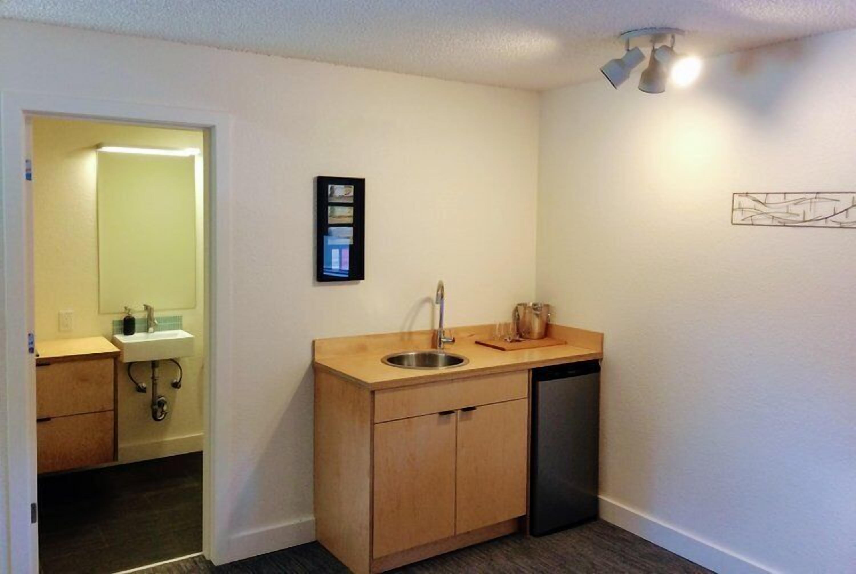 A compact kitchen with a sink, wooden cabinets, and a dishwasher.