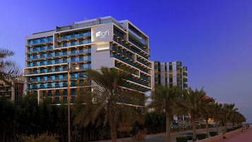 A modern hotel with multiple floors, balconies, and a well-lit facade.