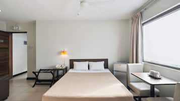 Een hotelkamer met een bed, nachtkastje, lamp en een raam met gordijnen.