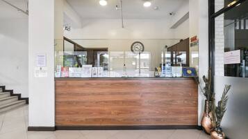 A reception desk with a wooden finish, a clock above it, and a glass partition.