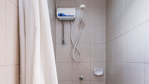 A bathroom with a shower, a hand dryer, and a soap dispenser.
