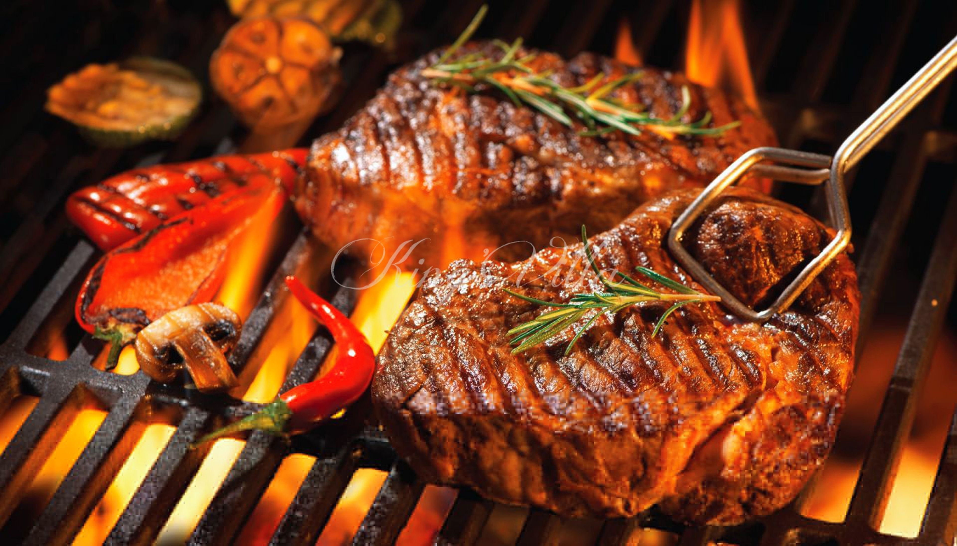 A steak on a grill with red peppers and a whole garlic bulb.