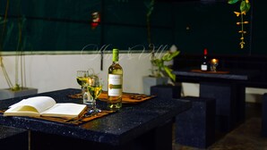 A table with an open book, a bottle of wine, and two glasses of white wine. - Kings Villa (Matara)