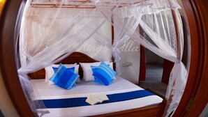 A bed with a canopy, pillows, and a book. - Kings Villa (Matara)