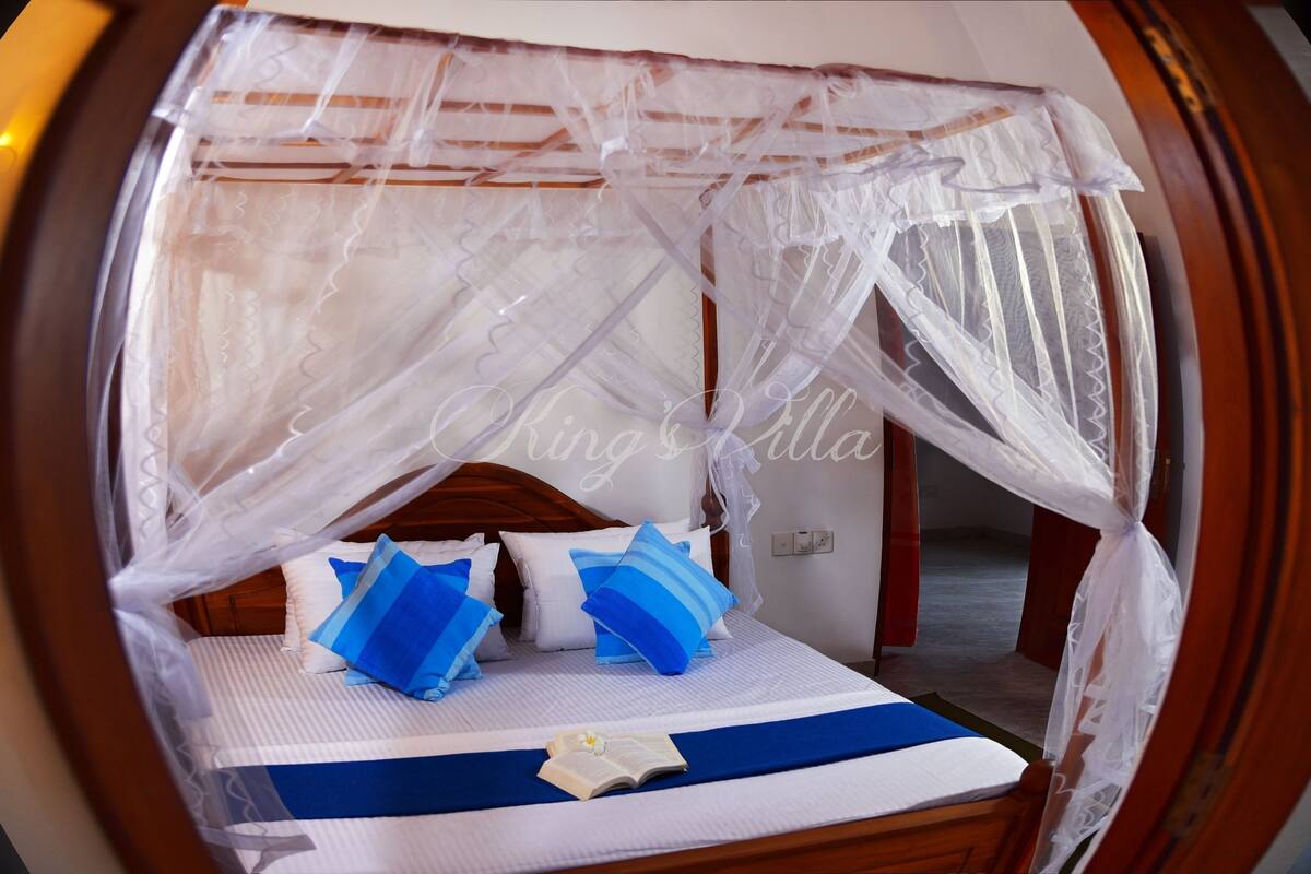 A bed with a canopy, pillows, and a book.