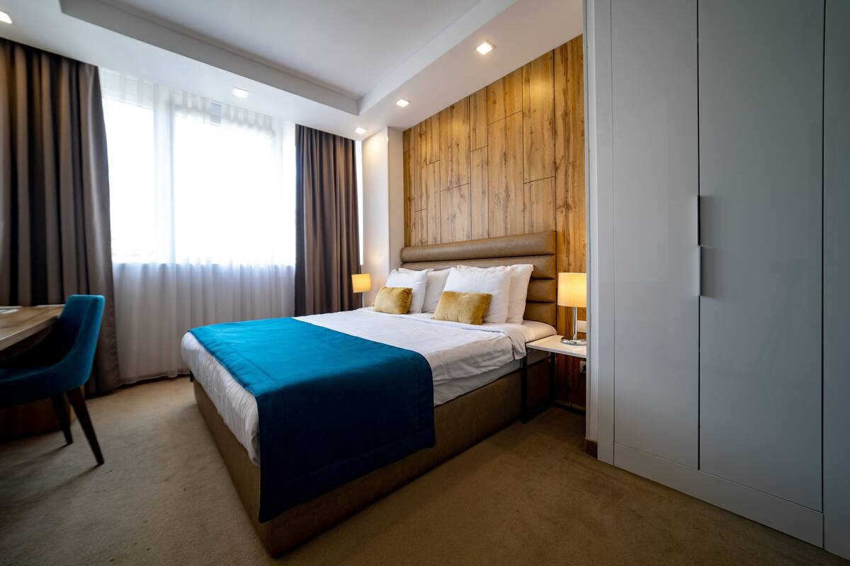 A hotel room with a large bed, a desk, and a wardrobe.