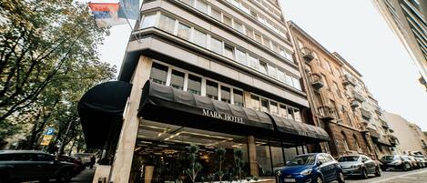 Un Hotel Mark con fachada moderna, amplias ventanas y un estacionamiento con coches.