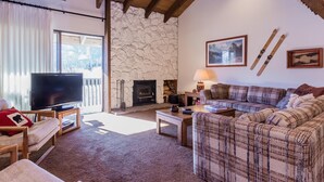A cozy living room with a stone fireplace, a television, and a sofa. - Snowcreek 97 - Phase I (Mammoth Lakes)