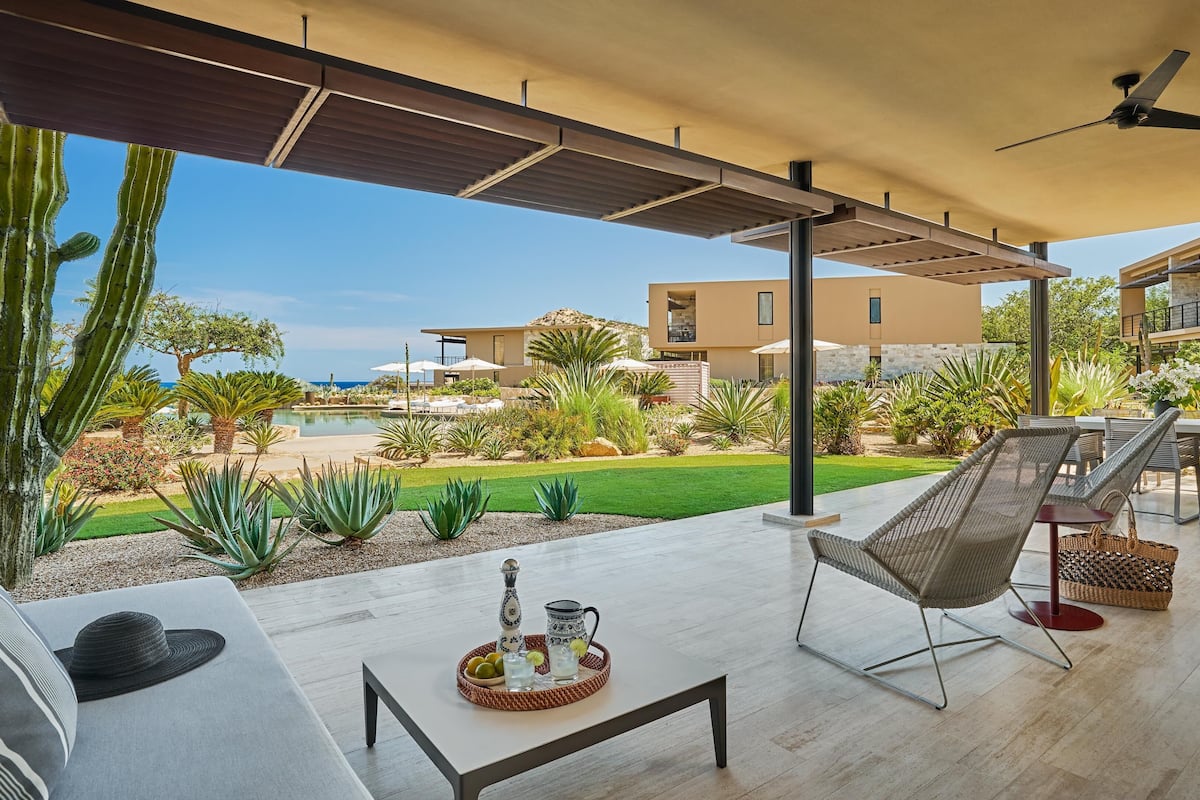 A modern outdoor patio with a pool, lounge chairs, and a dining area.