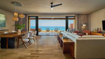 A modern living room with a view of the sea, a dining area, and a seating area with a sofa and chairs.