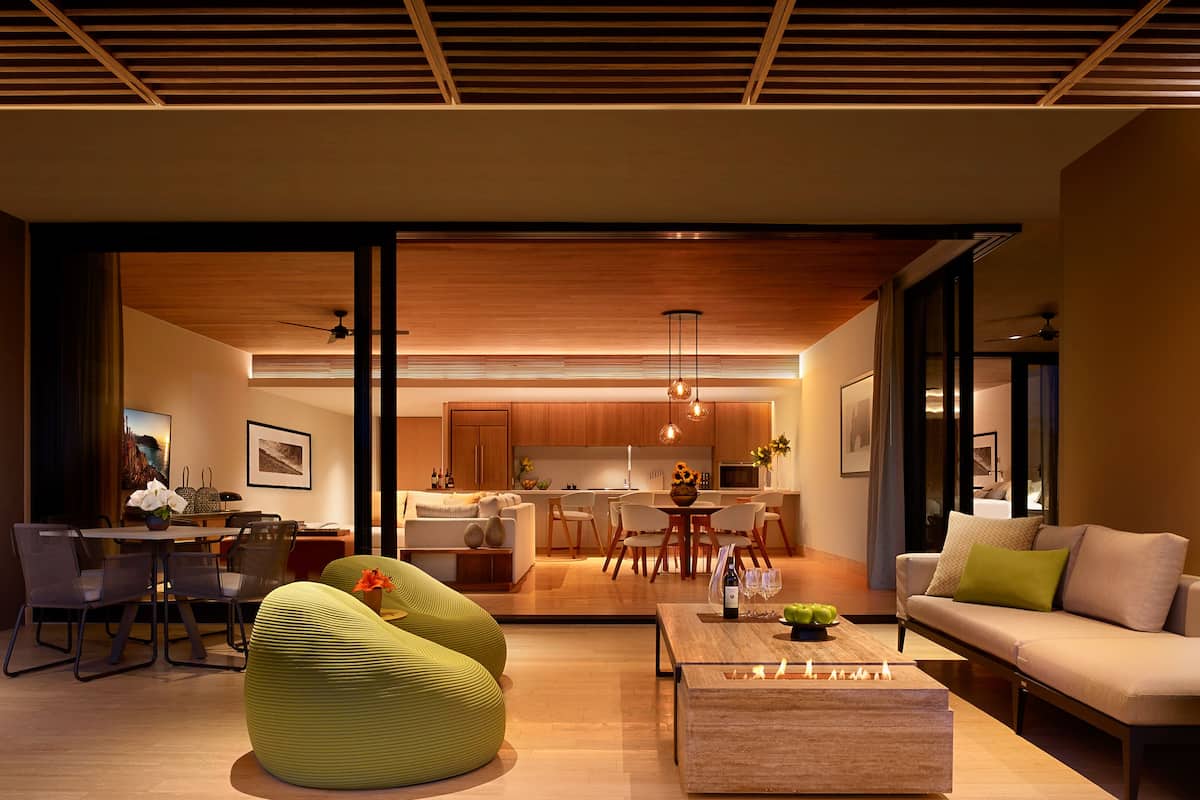 A modern living room with a sofa, a coffee table, and a dining area with chairs and a table.