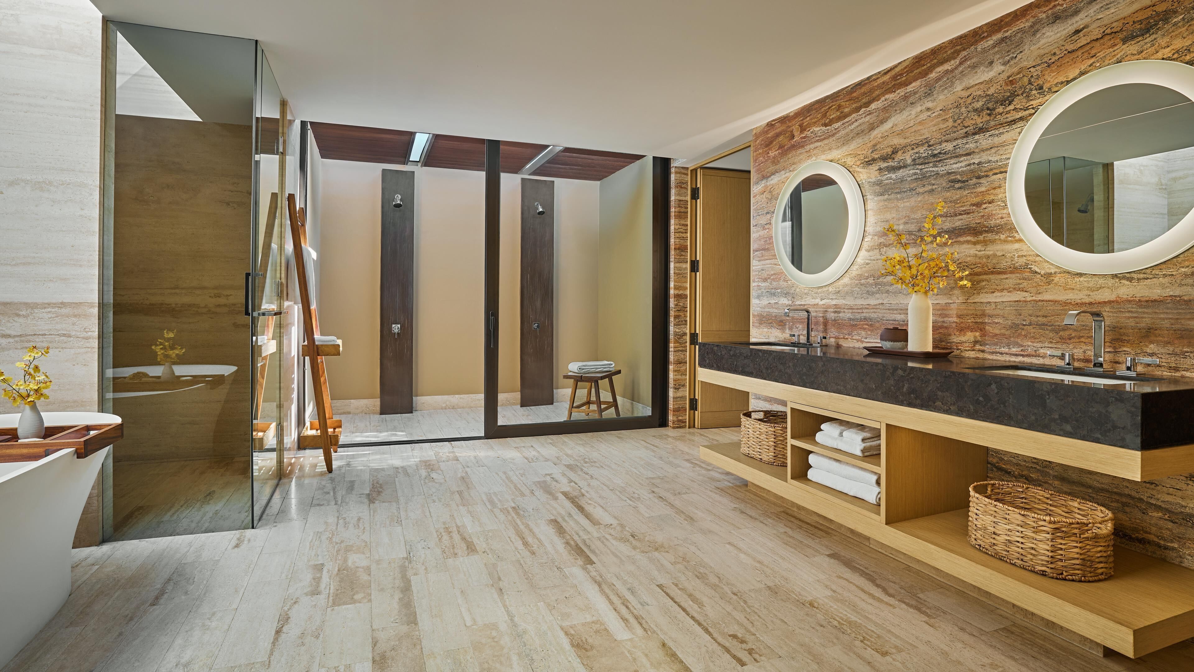 A modern bathroom with a large mirror, wooden vanity, and a glass shower enclosure.