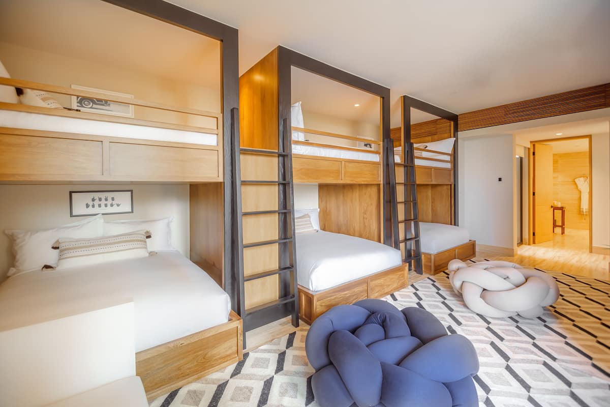 A modern hotel room with bunk beds, a sofa, and a patterned rug.