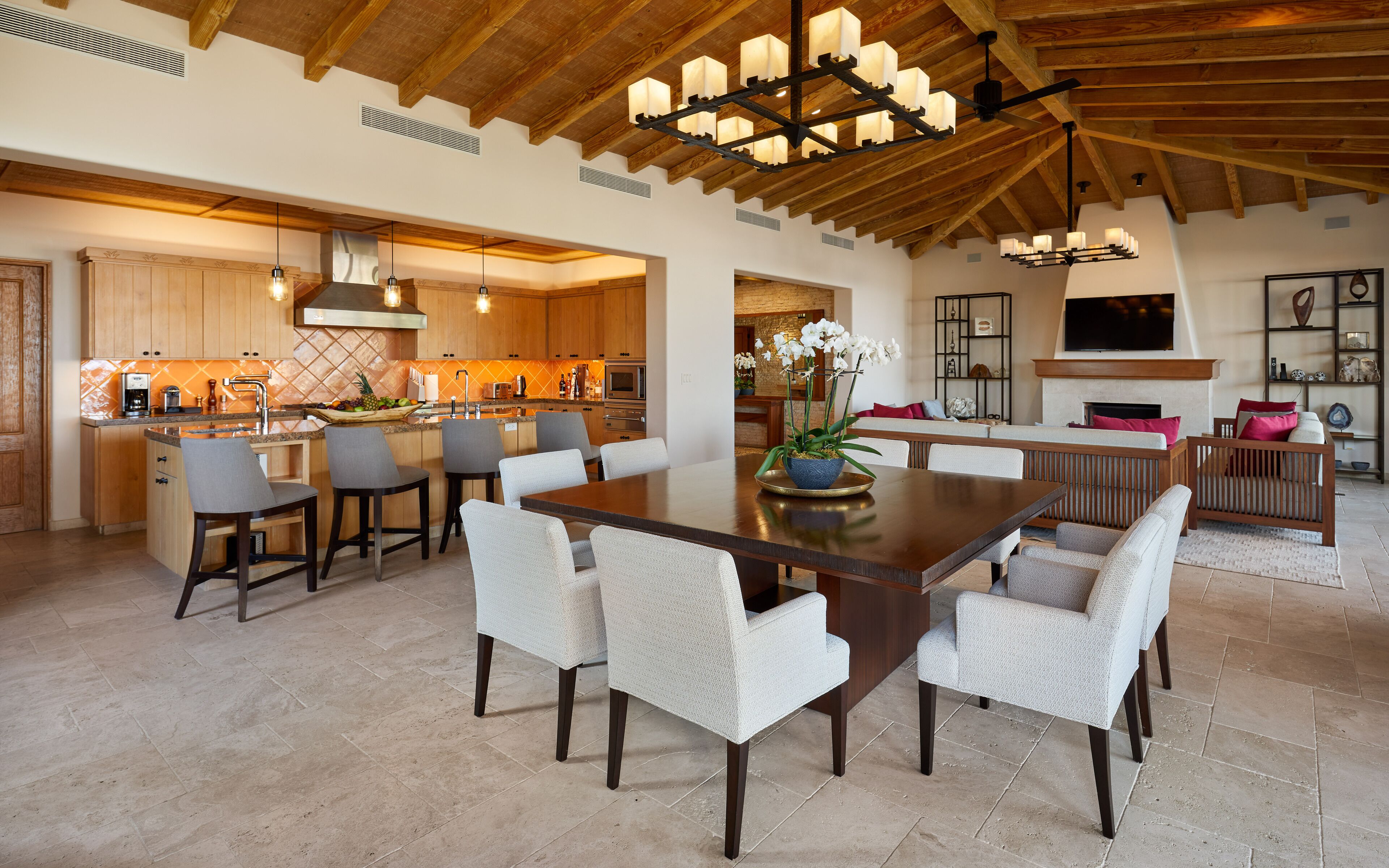 A spacious kitchen with wooden cabinets, a dining area with a large table and chairs, and a living area with a fireplace and seating.