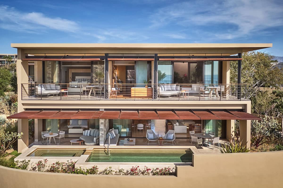 A modern two-story house with a balcony, outdoor seating, and a swimming pool.